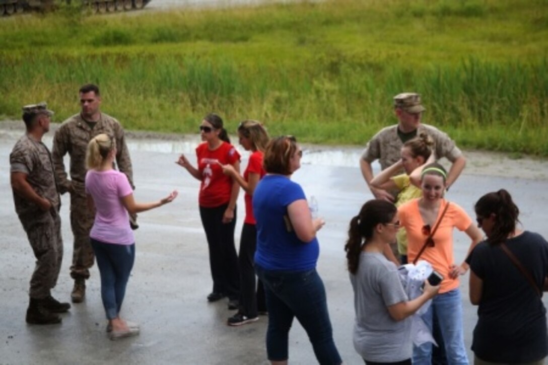 Marines and spouses socialize while waiting to ride on an M1A1 Abrams tank during Spouse Appreciation Day at range SR-10 aboard Camp Lejeune, N.C., June 2, 2015. 2nd Tank Battalion put on an event in which the spouses would participate in events to give a better understanding of what their husbands experience on a day-to-day basis.
