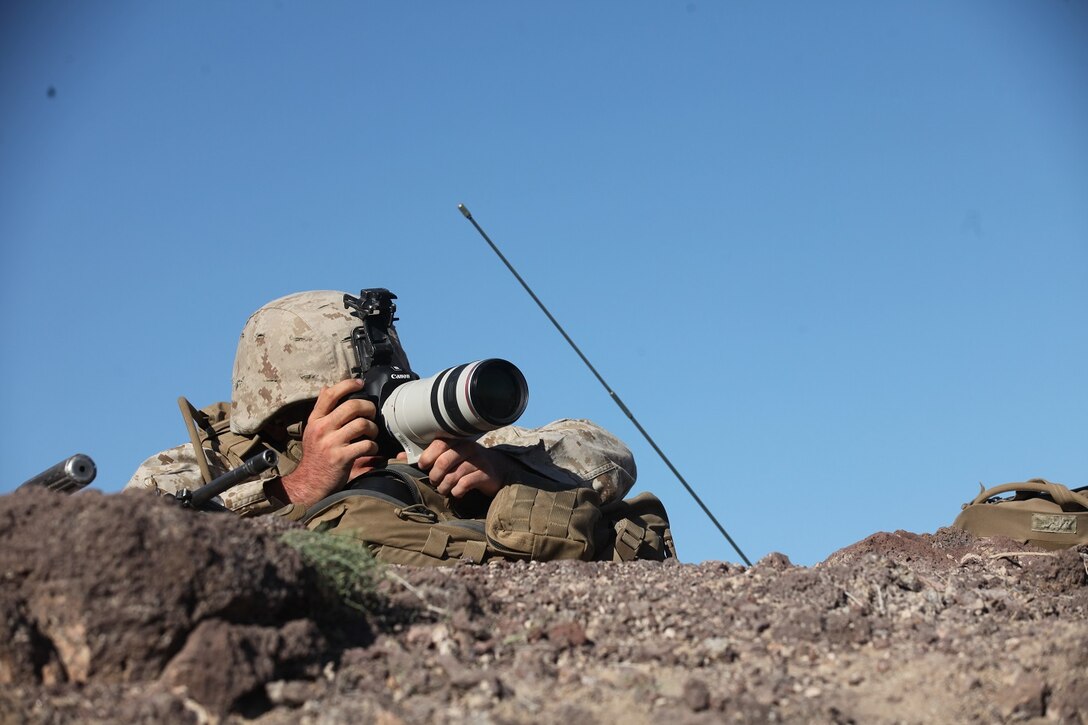 A forward observer with 1st Battalion, 7th Marine Regiment, 1st Marine Division, I Marine Expeditionary Force, photographs target positions for intelligence during 1/7’s Marine Corps Combat Readiness Evaluation aboard Marine Corps Air Ground Combat Center Twentynine Palms, Calif., June 9, 2015. Marines from 1/7 and 2nd battalion, 7th Marine Regiment are currently in preparation for deployment with the Special Purpose Marine Air Ground Task Force (SPMAGTF) scheduled to depart in support of Operation Inherent Resolve later this year.
