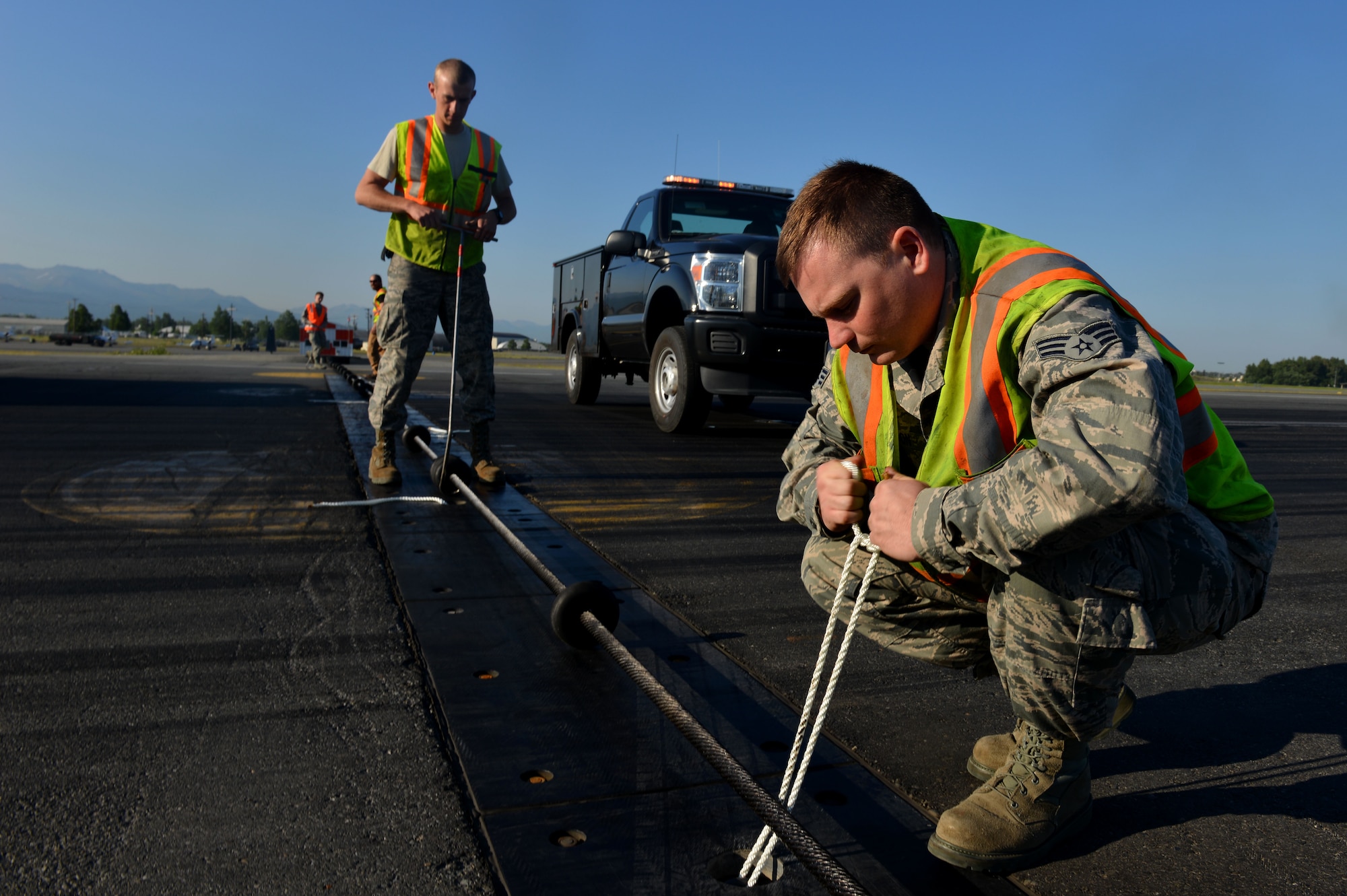Robert Gordon, a power production journeyman with the 773d Civil Engineering Squadron, ties a rope which helps hold the cable for the BAK-12 aircraft arresting system.The BAK-12s on the flightline of Joint Base Elmendorf-Richardson are designed to bring out-of-control aircraft to a safe stop with minimal damage. (U.S. Air Force photo/Airman 1st Class Kyle Johnson)