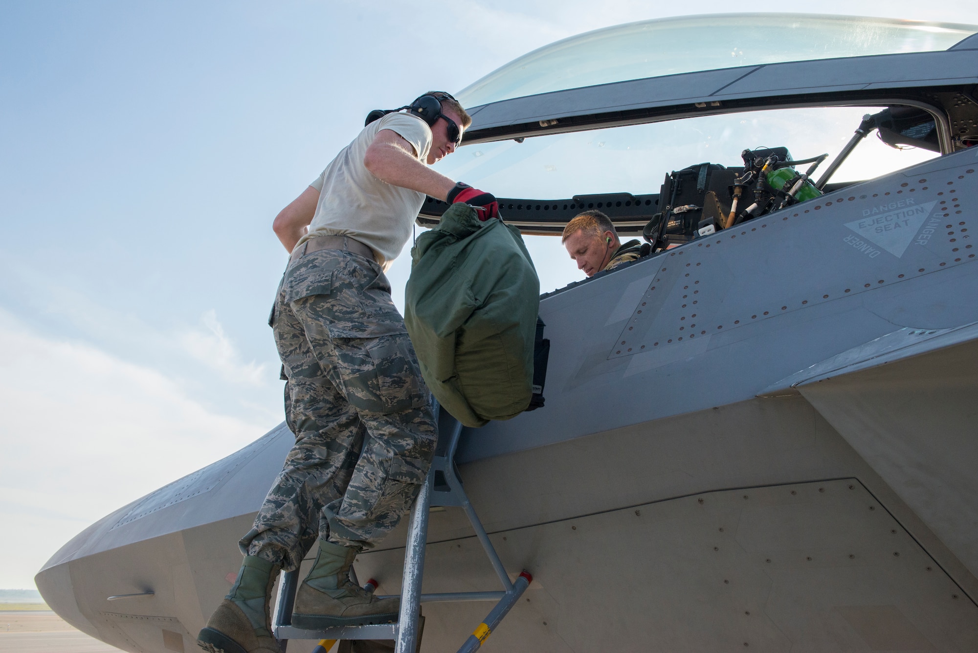 Senior Airman Craig Lively, 94th Aircraft Maintenance Unit Crew Chief, Joint Base Langley-Eustis, hands Col. Pat McAtee, 192nd Fighter Wing Operations Group commander, his flight bag during Exercise Northern Edge 15 at JBER, Alaska, June 16, 2015. Pilots and maintainers from the 192nd Fighter Wing, Virginia Air National Guard and active duty Airmen from the 1st Fighter Wing, Joint Base Langley-Eustis are participating in the two-week training exercise. Northern Edge 2015 is Alaska’s premier joint training exercise designed to perfect mission operations, techniques and procedures as well as enhance interoperability across all military services, Reserves and Air National Guard forces. (U.S. Air Force photo by Staff Sgt. Jonathan Garcia/Released)
