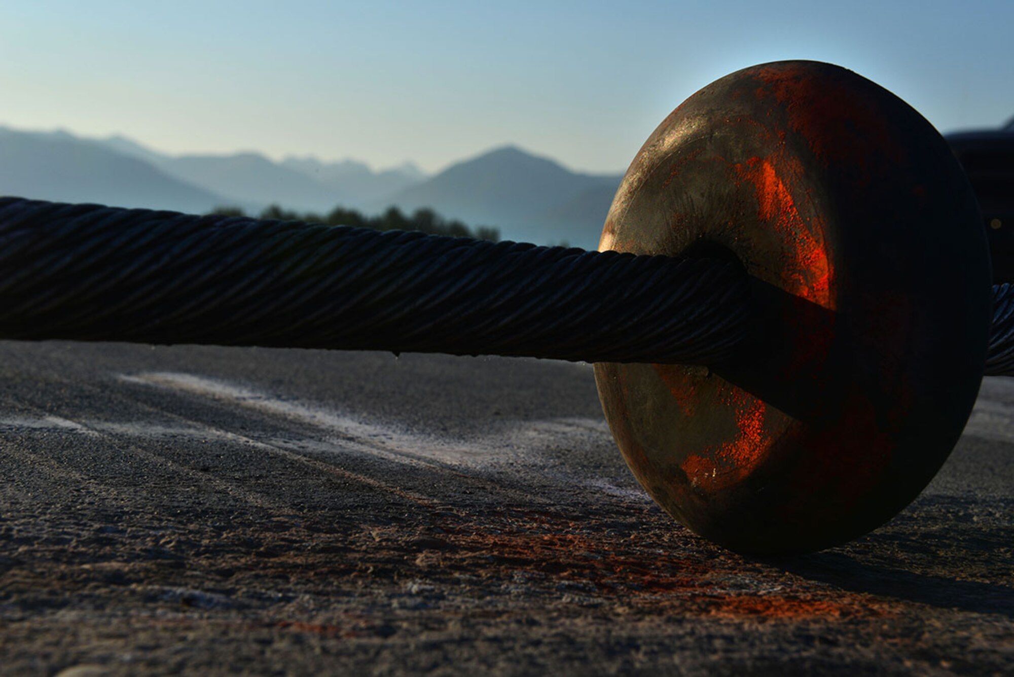 An orange ‘donut’ holds a steel cable two inches off the ground on the Joint Base Elmendorf-Richardson flightline. An aircraft’s tailhook would grab the cable in the event of an emergency, and is one part of the BAK-12 aircraft arresting system. The donuts in the center of the runway are spray-painted so a pilot can more easily hook the center of the cable. (U.S. Air Force photo/Airman 1st Class Kyle Johnson)