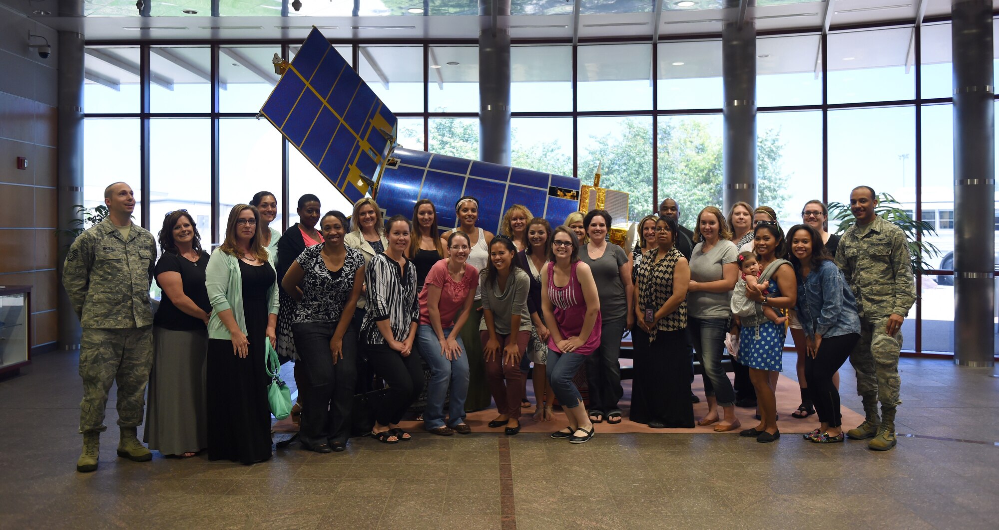 Military members and Buckley Air Force Base spouses pose for a group photo as part of the first Spouse Appreciation tour July 17, 2015, on Buckley Air Force Base, Colo. The group started their tour at the 460th Space Wing headquarters building and then made their way to the Mission Control Station, radomes and Army Aviation Support Facility. (U.S. Air Force photo by Airman 1st Class Emily E. Amyotte/Release)