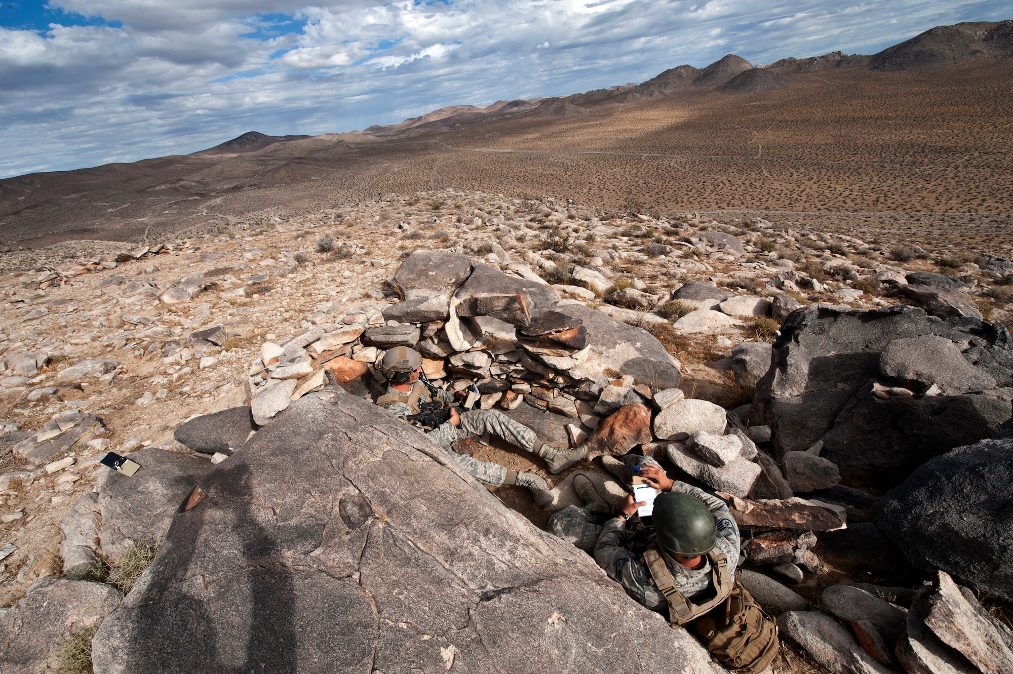 Tactical Air Control Party members from the 7th Air Support Operations Squadron, Fort Bliss, Texas, monitor radios from a defensive fighting position while Joint Terminal Attack Controllers direct incoming aircraft to simulated targets throughout the National Training Center at Fort Irwin, Calif., June 12, 2015. Exercise Green Flag runs at this location ten times annually, and places JTACs on the ground in support of Army Brigade Combat Teams receiving vital pre-deployment training. (U.S. Air Force photo by Senior Airman Joshua Kleinholz)