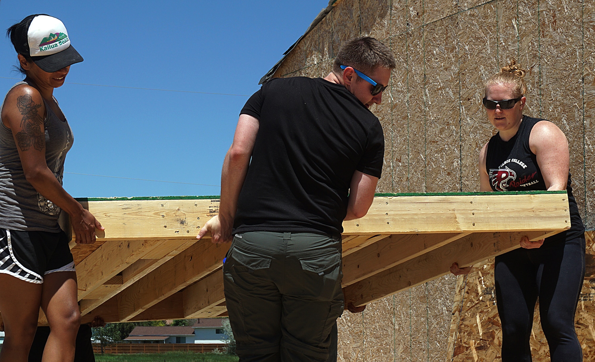 Senior Airmen Gloria Moctezuma, 90th Security Support Squadron; Alexander Gunter, 90th Missile Wing Protocol Office; and Staff Sgt. Aubrie Jones, 90th SSPTS, carry a wall into place during a Habitat for Humanity build June 14, 2015. The walls were constructed at Central High School in Cheyenne, Wyo., and transported to the build site. Mighty Ninety Airmen volunteered their time to help construct the house in Cheyenne, Wyo. (U.S. Air Force photo by Airman 1st Class Brandon Valle)