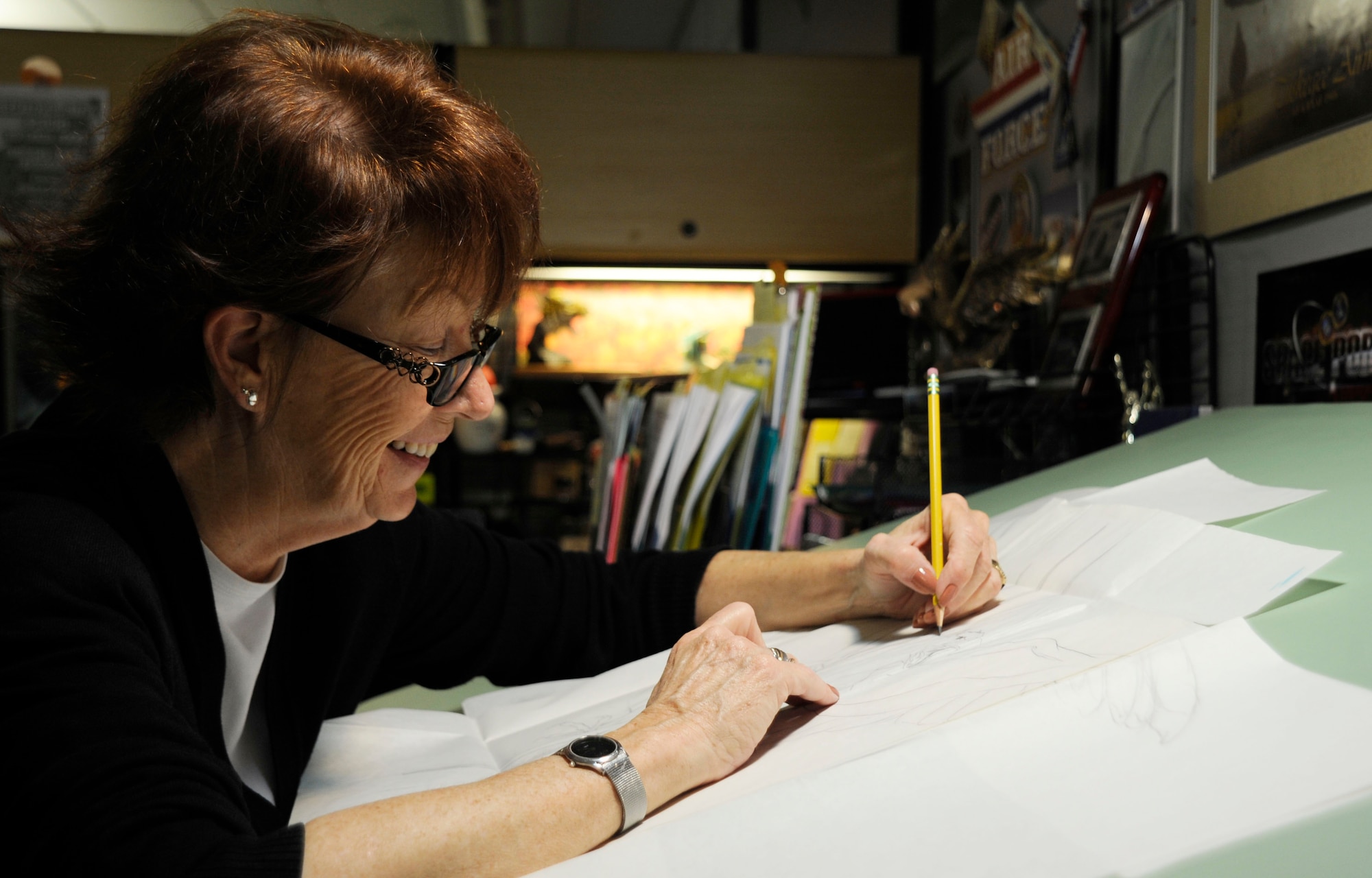 Jan Kays, 30th Space Wing visual information specialist, works on a griffin drawing in her office, June 11, 2015, Vandenberg Air Force Base, Calif. In the 15 years that Kays has worked in the graphics department at Vandenberg, she has had a profound impact on how the base is perceived by creating recognizable and aesthetically pleasing graphics. (U.S. Air Force photo by Airman 1st Class Ian Dudley/Released)