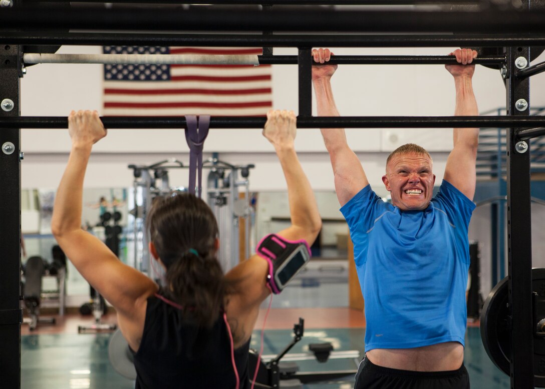 Shonda Nichols, spouse of Tech. Sgt. Aaron Nichols, 90th Civil Engineer Squadron, and Lt. Col. Dan Berg, 90th Operations Support Squadron director of operations, perform pull-ups during a workout at the Independence Hall Fitness Center on F.E. Warren Air Force Base, Wyo., May 20, 2015. Nichols and Berg are able to have more variety of workouts because of the new endurance training equipment. (U.S. Air Force photo by Lan Kim)