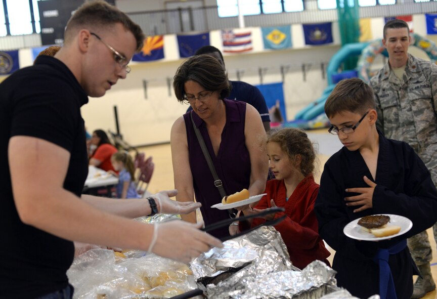 Airmen from the 100th Communications Squadron serve Team Mildenhall family members food during a Hearts Apart event at the Hardstand Fitness Center June 17, 2015, on RAF Mildenhall, England. The Hearts Apart event is held on a monthly basis for families of deployed Airmen. (U.S. Air Force photo by Senior Airman Christine Halan/Released)