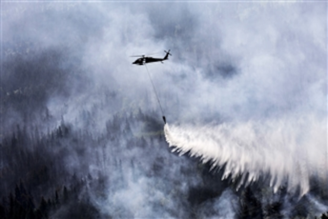 An Alaska Army National Guard UH-60 Black Hawk helicopter drops gallons of water from a bambi bucket onto the Stetson Creek fire near Cooper Landing in Alaska, June 17, 2015.Two Black Hawk helicopters flew 200 bucket missions, dumping more than 144,000 gallons of water on the 300-acre fire on the Kenai Peninsula.