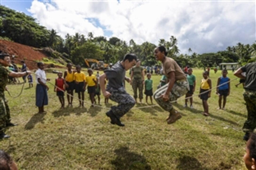 U.S. Navy Seaman Anaseini Taufa, right, and members of the Japan Self Defense Force jump rope in front of children from the Viani Primary School during Pacific Partnership 2015 in Vavua Levu, Fiji, June 17, 2015. The crew of the Military Sealift Command hospital ship USNS Mercy helped build a classroom at the school and celebrated with a ribbon-cutting ceremony.