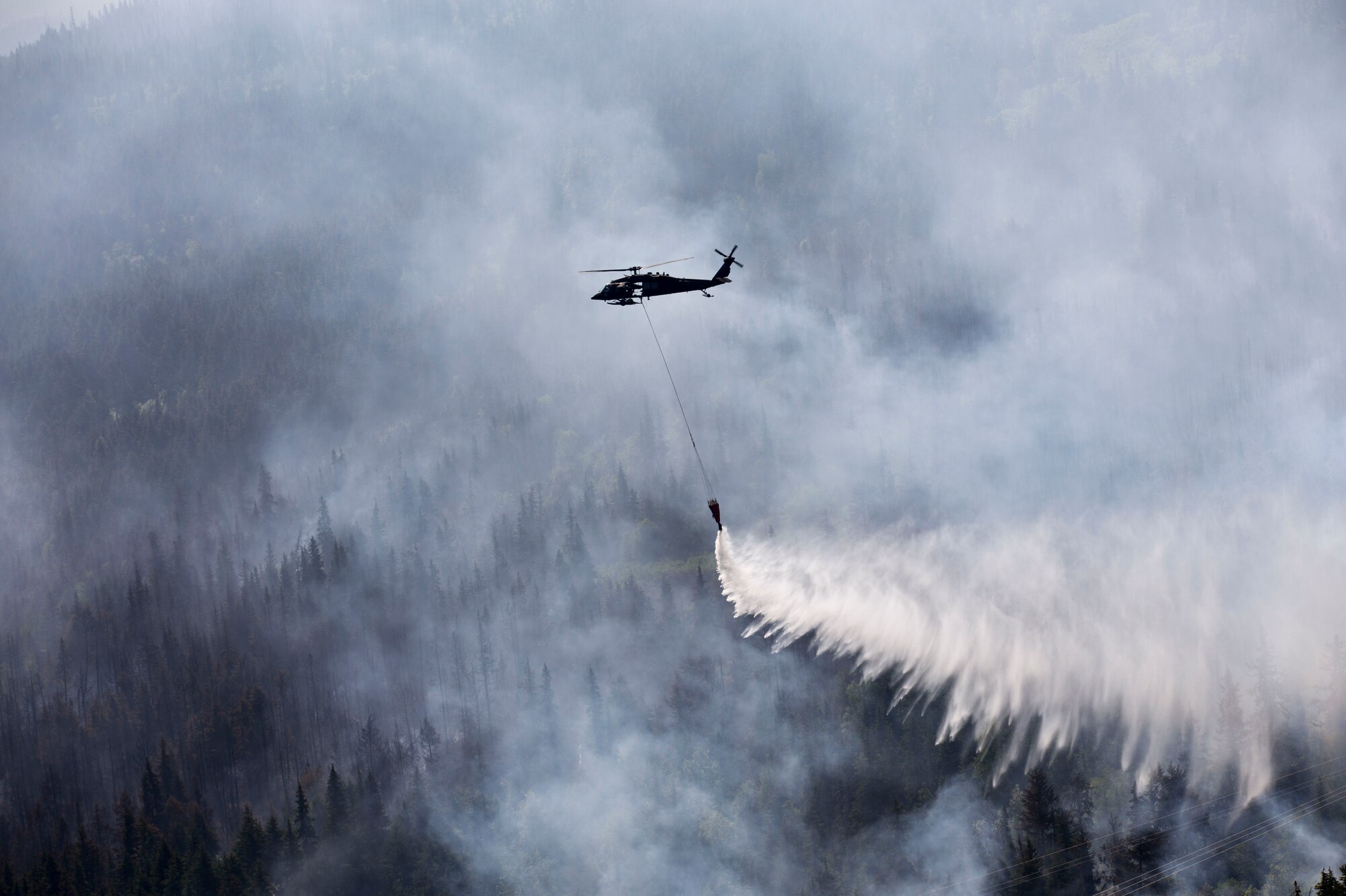 An Alaska Army National Guard UH-60 Black Hawk helicopter from 1st Battalion, 207th Aviation Regiment, drops approximately 700 gallons of water from a “Bambi Bucket” on to the Stetson Creek Fire near Cooper Landing, Alaska, June 17. Two AKARNG Black Hawk helicopters flew a total of 200 bucket missions, dumping more than 144,000 gallons of water on the 300-acre Stetson Creek Fire on the Kenai Peninsula. (U.S. Army National Guard photo by Sgt. Balinda O’Neal)