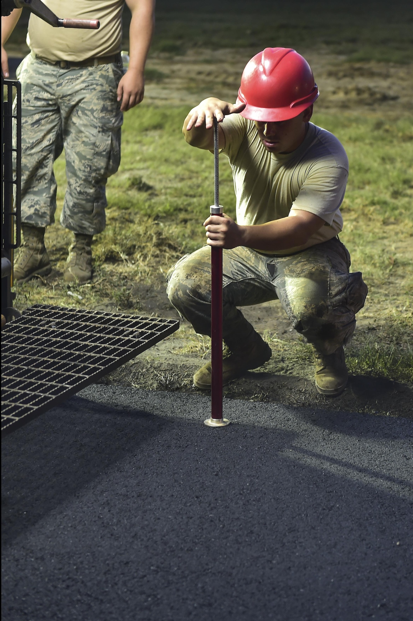 Senior Airman Juan Puerta, 823rd RED HORSE Squadron pavements and construction equipment journeyman, measures the depth of the asphalt while paving a portion of Independence Road at Hurlburt Field, Fl., June 16, 2015. The re-construction project repaired multiple pot holes and cracks caused by pooling water. (U.S. Air Force photo/Senior Airman Jeff Parkinson)