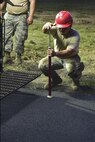 Senior Airman Juan Puerta, 823rd RED HORSE Squadron pavements and construction equipment journeyman, measures the depth of the asphalt while paving a portion of Independence Road at Hurlburt Field, Fl., June 16, 2015. The re-construction project repaired multiple pot holes and cracks caused by pooling water. (U.S. Air Force photo/Senior Airman Jeff Parkinson)