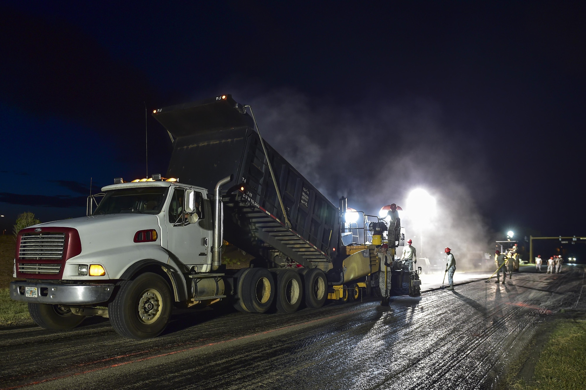 Airmen from the 823rd RED HORSE Squadron lay asphalt during a road re-construction project on Independence Road at Hurlburt Field, Fl., June 16, 2015. The re-construction project repaired multiple pot holes and cracks caused by pooling water. (U.S. Air Force photo/Senior Airman Jeff Parkinson)