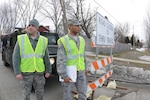 Air Force Staff Sgt. Donald Clarke, of the North Dakota Air National Guard's 119th Civil Engineer Squadron, and Air Force Senior Airman Gabriel Irvis, of the 119th Security Forces Squadron, watch for traffic at a traffic control point at an intersection being used for sandbag delivery April 5 in Fargo, N.D. Clarke and Irvis are making sure that unauthorized people are not using the route and the road is being kept clear for flood fighting resource delivery.