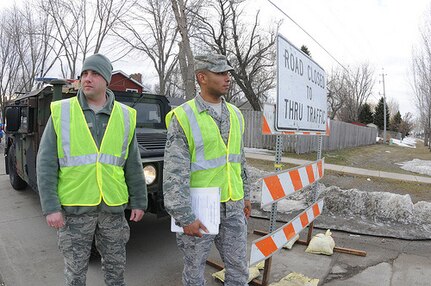 Air Force Staff Sgt. Donald Clarke, of the North Dakota Air National Guard's 119th Civil Engineer Squadron, and Air Force Senior Airman Gabriel Irvis, of the 119th Security Forces Squadron, watch for traffic at a traffic control point at an intersection being used for sandbag delivery April 5 in Fargo, N.D. Clarke and Irvis are making sure that unauthorized people are not using the route and the road is being kept clear for flood fighting resource delivery.