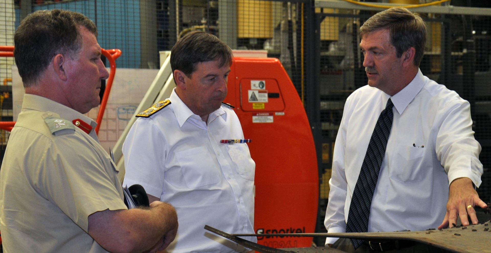 Naval Surface Warfare Center Dahlgren Division (NSWCDD) Electromagnetic Railgun Program Director Chester Petry describes the hypervelocity projectile's capability to UK Defense Attaché to the US, Maj. Gen. Richard Cripwell, left, and UK Royal Navy Second Sea Lord Vice Adm. Jonathan Woodcock, June 10. The second sea lord - responsible for the delivery of the British naval service's current and future personnel, equipment and infrastructure - visited NSWCDD with his delegation for briefings on various technological programs, including the electromagnetic railgun - a long-range naval weapon that fires projectiles using electricity instead of traditional gun propellants such as explosive chemicals. The hypervelocity projectile is a next-generation, guided projectile capable of completing multiple missions for gun systems such as the Navy 5-Inch, 155-mm, and future railguns. Woodcock and his delegation also toured the Potomac River Test Range - 715 acres of land and a 169-square-nautical-mile water area that stretches along the lower 51 miles of the Potomac River. The British officials looked out over the Potomac and saw firsthand how Dahlgren's gun test facility evolved and expanded to include numerous scientific and response-force missions serving all branches of the United States armed forces.