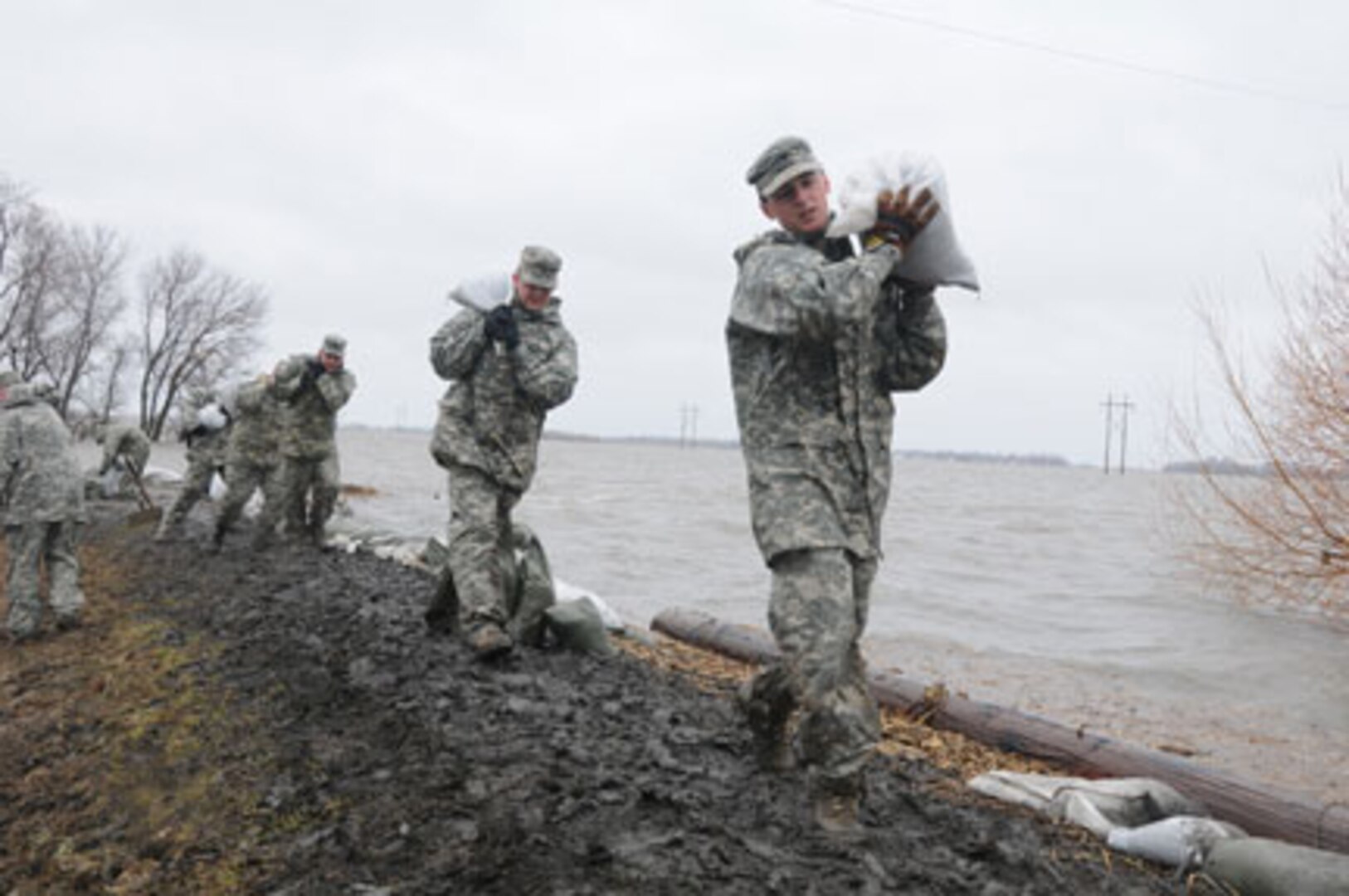 From right to left: Army Spc. Eric Wiederholt, Army Spc. Joshua Lanzdorf and
Army Spc. Randy Birchfield, all of the 815th Engineer Company, Detachment 2,
based in Lisbon, N.D., carry sandbags in the rain along a flood levee for
placement in a flood barrier April 10, 2011, at a rural farmstead in Cass
County, N.D. The Soldiers are members of a North Dakota National Guard quick
response force team that has been sent to the rural home, which has been
surrounded by miles of floodwater, by the Cass County tactical operations
center. About 500 Guardsmen are currently conducting flood operations in
North Dakota, with the vast majority in Cass County.