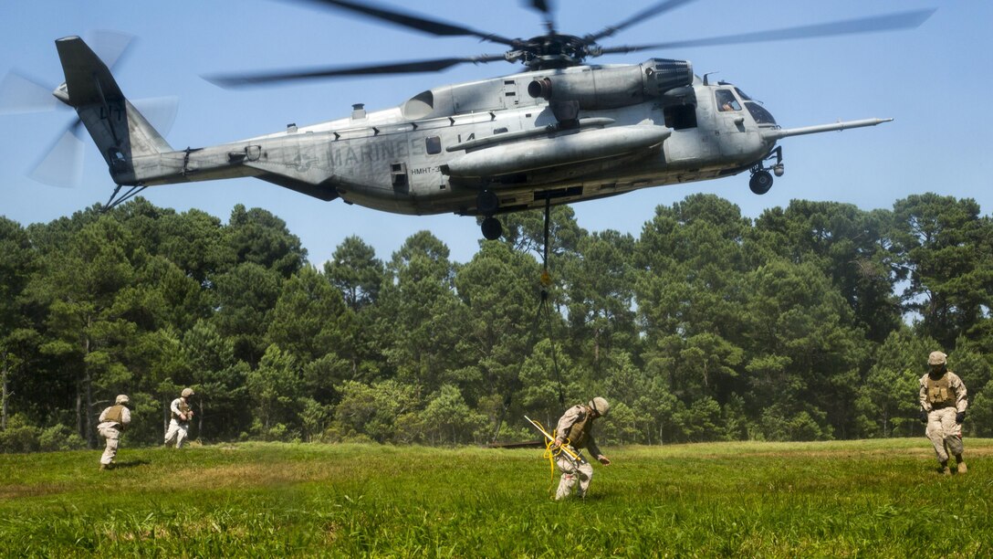 Marines with Combat Logistics Battalion 2 secure a beam, which is intended to simulate a 6,000 pound cargo load, to a CH-53E Super Stallion operated by Marines with Marine Heavy Helicopter Training Squadron 302 aboard Camp Lejeune, N.C., June 16, 2015. HMHT-302 teamed up with Combat Logistics Battalion 2 to give pilots and landing support specialists familiarization with operating equipment and performing external operations, skills that allow them to deliver and recover supplies and gear quickly and efficiently in deployed settings. (U.S. Marine Corps photo by Lance Cpl. Fatmeh Saad/Released)
