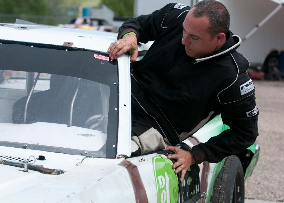 Maj. Neil Copenhaver, 20th Air Force deputy director of logistics, hops through the window into the driver’s seat of his stock car June 13, 2015, in Cheyenne, Wyo. Copenhaver passed down his previous car to his son after winning last year’s Warrior Class race with it. (U.S. Air Force photo by Airman 1st Class Malcolm Mayfield)