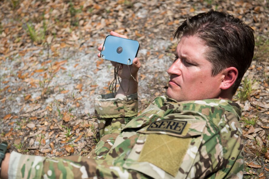 U.S. Air Force Staff Sgt. Ryan Hall, 18th Air Support Operations Group Survival, Escape, Resistance and Evasion specialist, aims a specialized mirror at an A-10C Thunderbolt II during a personnel recovery scenario during Exercise DRAGON STRIKE June 11, 2015, near Avon Park Air Force Range, Fla. Hall utilized the mirror by reflecting the sun to send a distress signal to the aircraft for the rescue exercise. (U.S. Air Force photo by Airman 1st Class Dillian Bamman/Released)