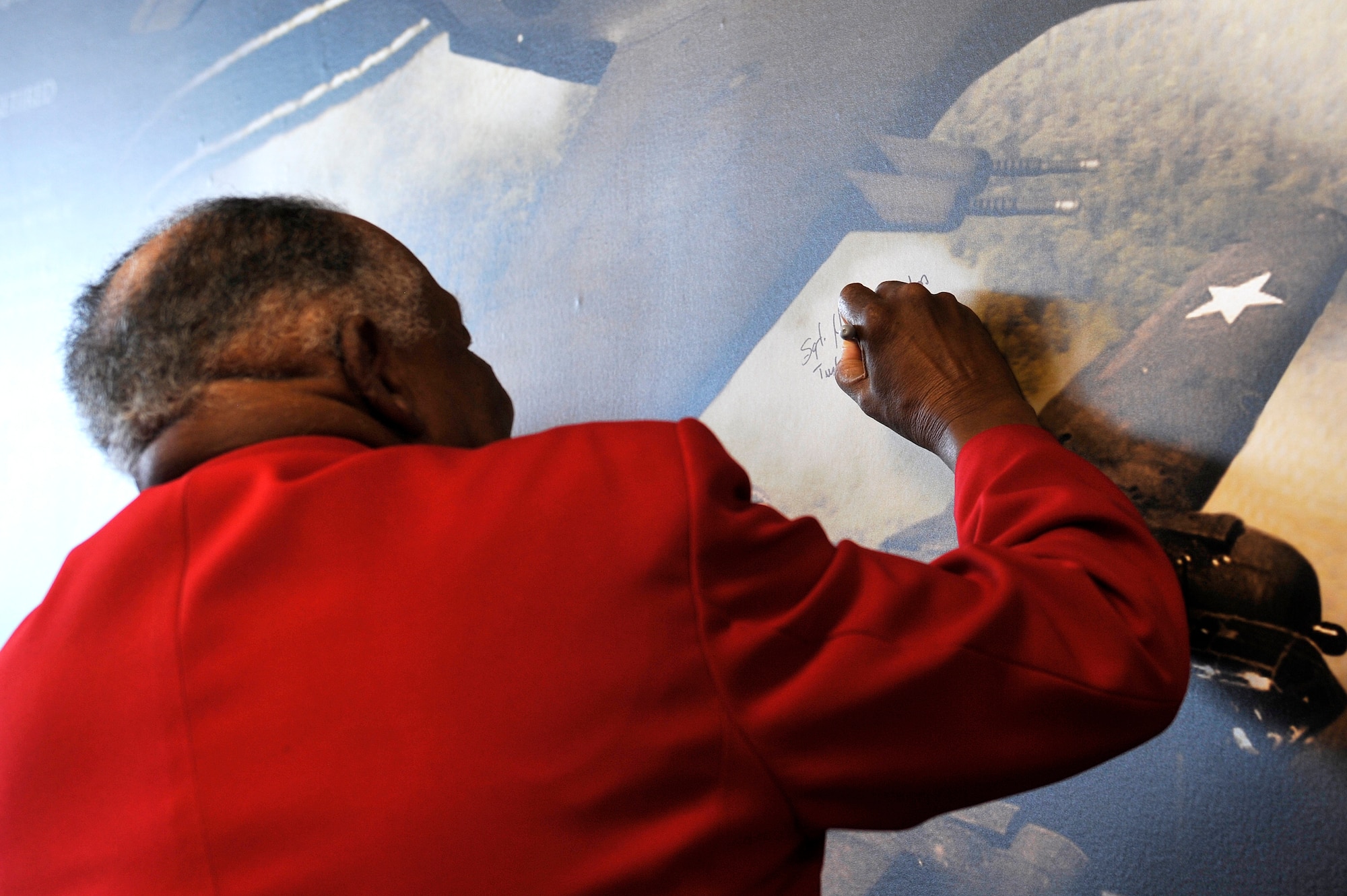 Harry Quinton, Tuskegee Airmen Inc. Tidewater Chapter member, signs the Tuskegee Airmen Mural at the Exchange at Langley Air Force Base, Va., June 18, 2015.Before being called Tuskegee Airmen, African American pilots originally formed the 332nd Fighter Group and the 477th Bombardment Group of the United States Army Air Forces. (U.S. Air Force photo by Senior Airman Breonna Veal/Released)