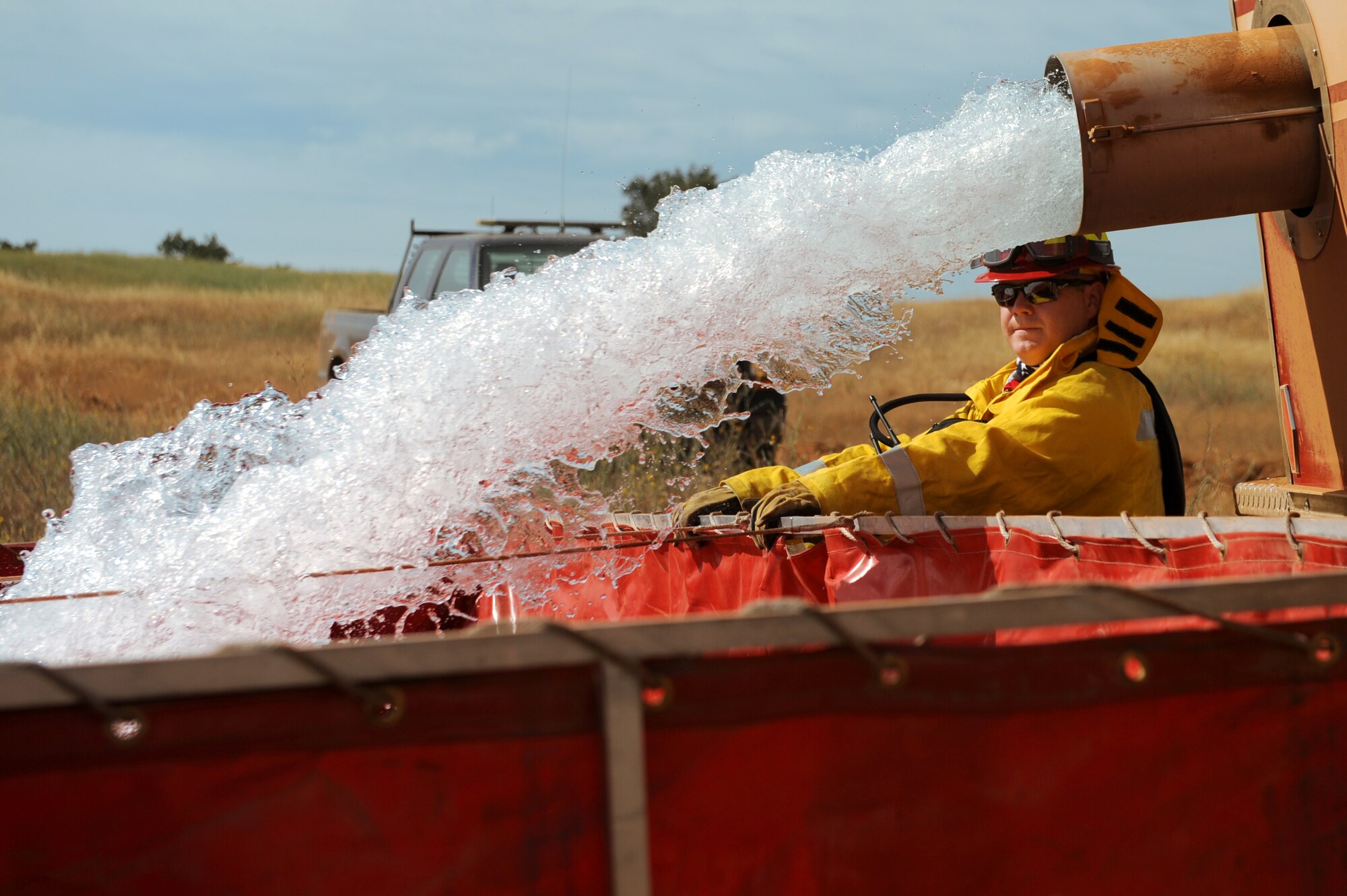 Staff Sgt. Vincent Kinard, 9th Civil Engineer Squadron firefighter, assists in filling a mobile water station for a controlled burn at Beale Air Force Base, California on June 17, 2015. The burn consumed approximately 800 acres in an effort to renew cattle grazing land and control vegetation growth. (U.S. Air Force photo by Preston L. Cherry)