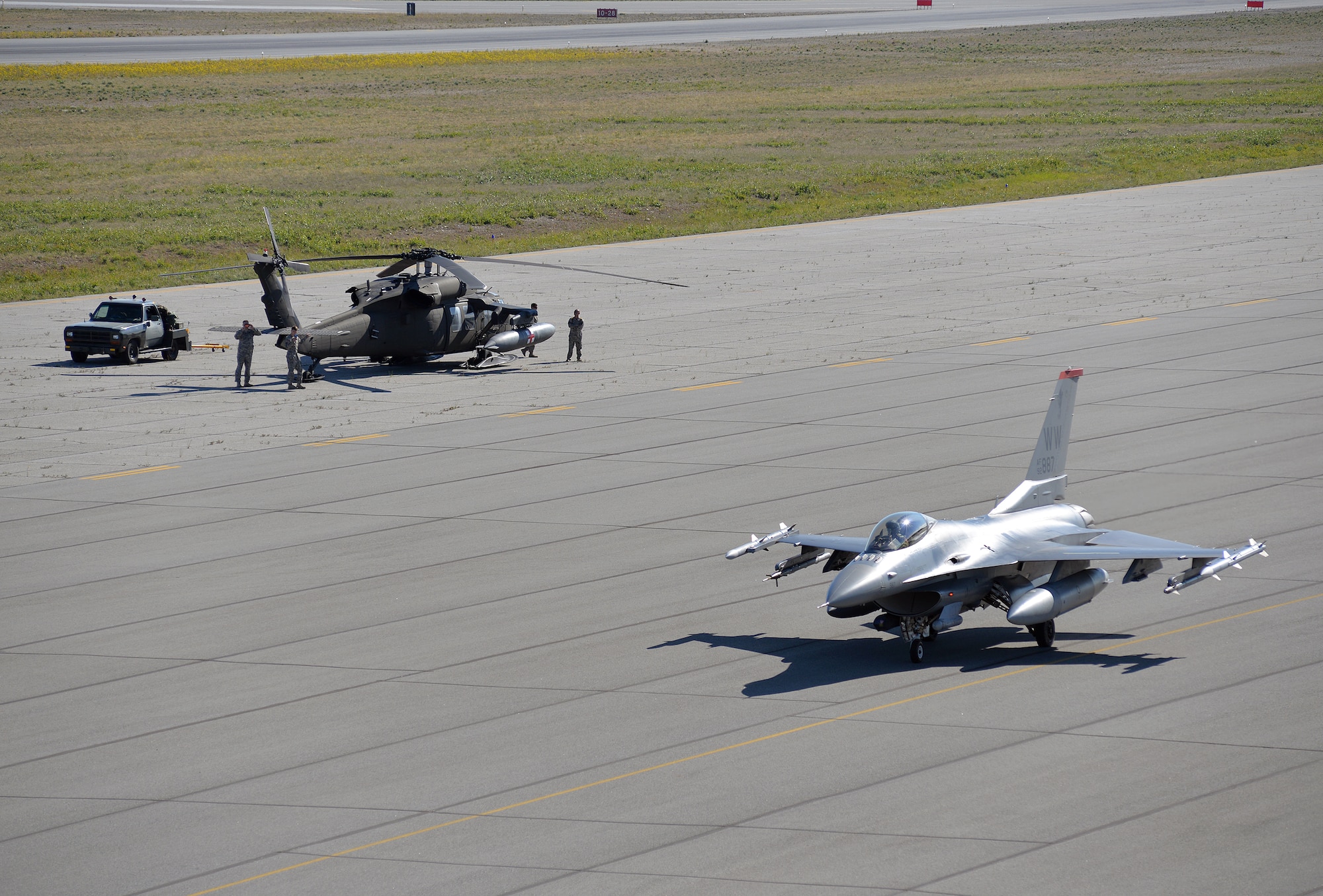 U.S. Army Soldiers working on a UH-60 Black Hawk helicopter take a brief break from work to watch a U.S. Air Force F-16 Fighting Falcon taxi past their position as the fighter pilot prepares to take off from Allen Army Airfield at Fort Greely, Alaska, shortly before an airfield seizure scenario is executed as part of Exercise Northern Edge, June 17, 2015. Northern Edge 2015 is Alaska's premier joint training exercise designed to practice operations, techniques and procedures as well as enhance interoperability among the services. Thousands of Airmen, Soldiers, Sailors, Marines and Coast Guardsmen from active duty, reserve and National Guard units are involved. (U.S. Air Force photo by Master Sgt. Karen J. Tomasik/Released)
