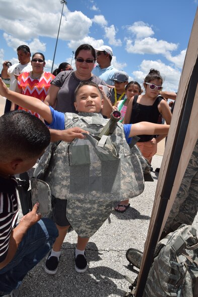 Staff Sgt. Danny Cruz, 433rd Security Forces Squadron Combat Arms Training and Maintenance instructor assists a potential recruit on June 7, 2015 put on the protective gear a security forces Airmen wears while deployed in contingency operations. Security Forces had a booth and equipment set-up for families to view and enjoy during the 433rd Airlift Wing's Family Day at Joint Base San Antonio-Lackland, Texas.  (U.S. Air Force photo by Tech. Sgt. Carlos J. Trevino) 