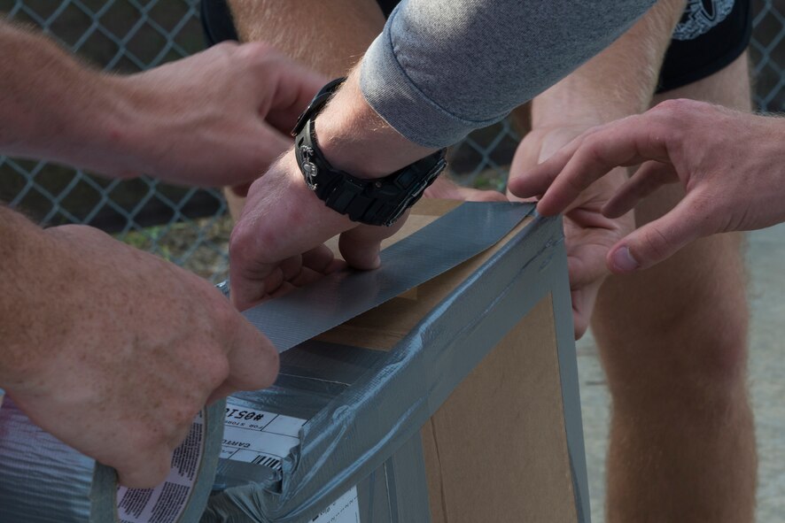 Airmen from the 23d Civil Engineer Squadron tape a boat together during the Build-a-Boat competition June 18, 2015, at Moody Air Force Base, Ga. Five team had 45 minutes to build their boat before racing across the outdoor pool. (U.S. Air Force photo by Airman 1st Class Kathleen D. Bryant)