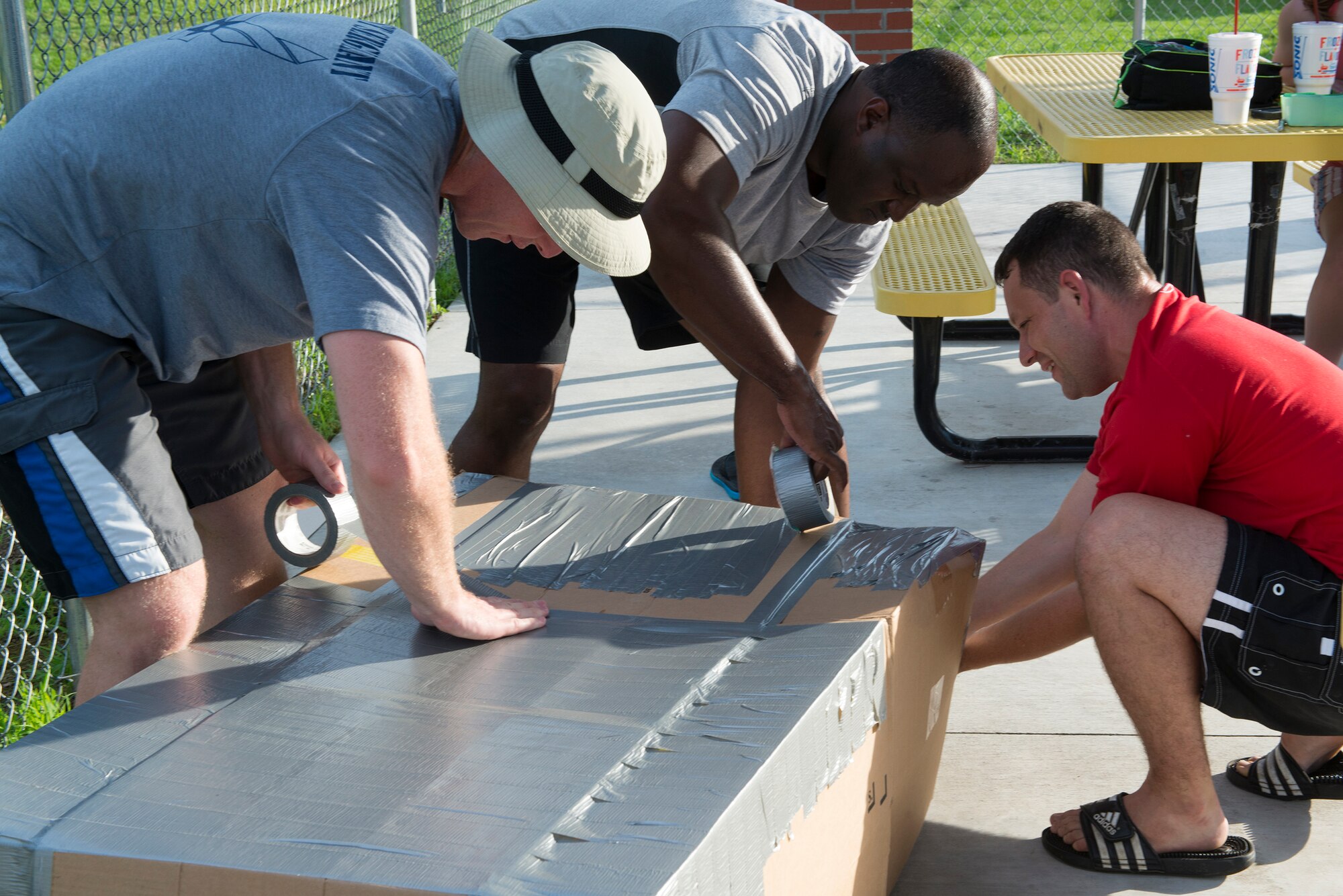 The First Sergeant team builds a boat during the Build-a-Boat competition June 18, 2015, at Moody Air Force Base, Ga. Five teams used three cardboard boxes, two box cutters, two rolls of duct tape and a paddle to build a boat and race across the outdoor pool. (U.S. Air Force photo by Airman 1st Class Kathleen D. Bryant)