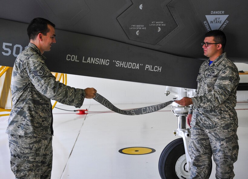 Staff Sgt. Danny Pierera and Senior Airman Mario Gonzalez, 33rd Aircraft Maintenance Squadron dedicated crew chiefs, unveil Col. Lansing Pilch’s name on the 33 FW’s flagship June 19, on Eglin Air Force Base, Fla. Pilch is a command pilot with more than 2,700 hours in various fighter and heavy aircraft, including more than 900 hours in the F-22A. Prior to arriving here, he served as the commander of the 3rd Operations Group, Joint Base Elmendorf-Richardson, Alaska. (U.S. Air Force photo/Staff Sgt. Marleah Robertson)