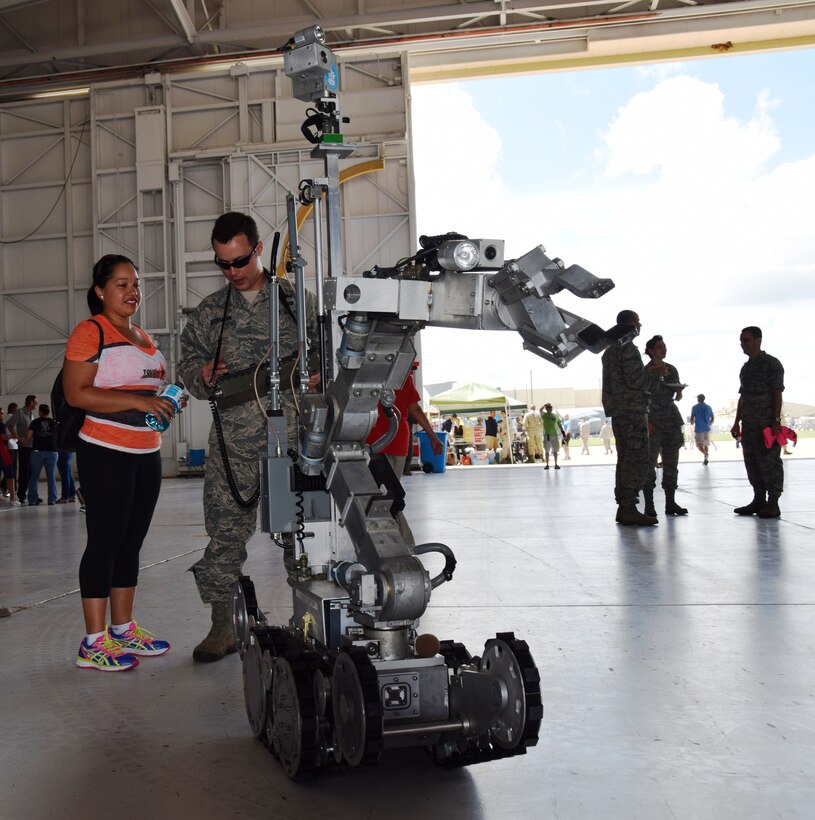 Tech Sgt. Kim Herrera(left),  433rd Airlift Wing Historian, listens to Senior Airman Ryan Beckman, an explosive ordnance disposal technician with the 433 Civil Engineering Squadron, explain the controls used to operate a bomb disposal robot during the 433rd Airlift Wing Family Day on June 7, 2015 at Joint Base San Antonio-Lackland, Texas.  (U.S. Air Force photo by Tech. Sgt. Carlos J. Trevino)   