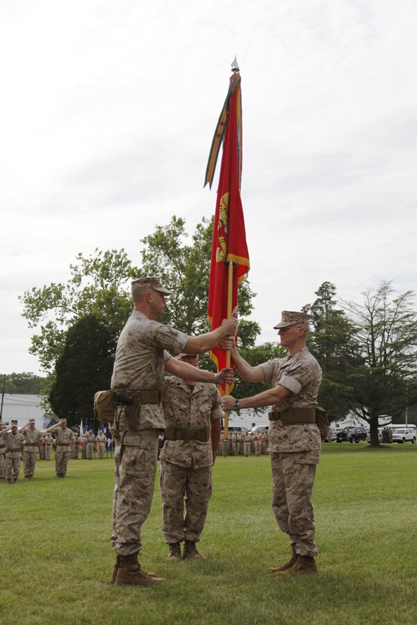 U.S. Marine Col. James M. Bright, Marine Corps Security Force Regiment outgoing commander (right), hands the regimental colors to Col. John W. Evans Jr., incoming regimental commanding officer (left), during a change-of-command ceremony aboard Naval Weapons Station Yorktown, Va., June 19, 2015. The exchange of the regimental colors represents the passing of command from the outgoing to the incoming commander. (U.S. Marine Corps photo by Sgt. Esdras Ruano/Released)