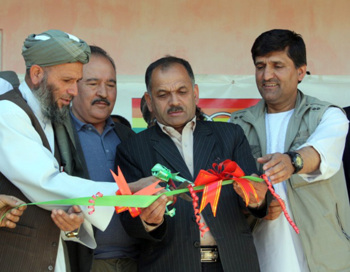 Haji Abdul Robate Qahir (far left), the Director of the Baston Seed Company,
cuts the ribbon across the entrance of his new soybean processing facility
in Bagram, April 2, 2011. Mohammad Sharif Sharif (back left), an engineer
with Soy Nutrition Services Afghanistan, Abdul Kabir Farzam (center), the
Parwan Director of Agriculture, Irrigation and Livestock, and Shamir Amiri
(right), the Panjshir DAIL hold the ribbon for Qahir.