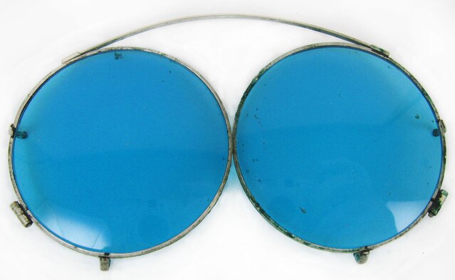 These blue-tinted clip-on sunglasses were worn by 1st Lt. Carroll DeWitt McClung with his prescription eyeglasses. They are approximately 3-3/8 - 4 inches in width and were manufactured to stretch to fit and clip onto various size prescription eyeglass frames. This style of clip-on sunglasses is still manufactured and used today. (U.S. Air Force photo)