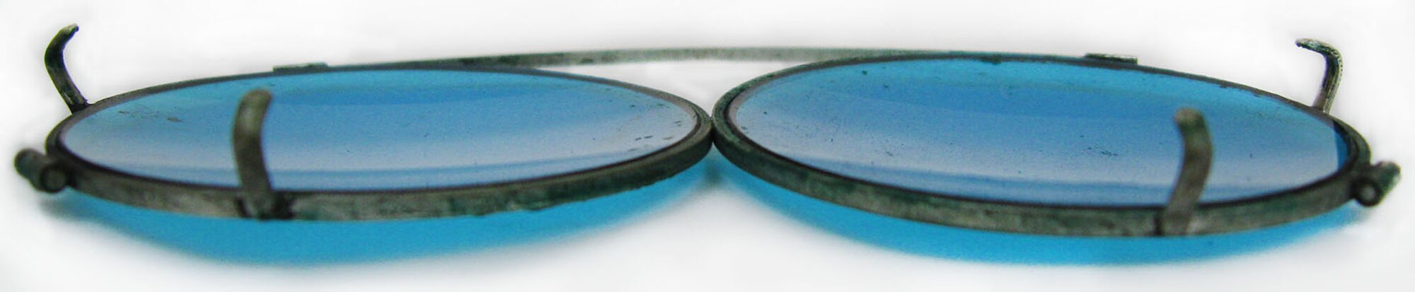 These blue-tinted clip-on sunglasses were worn by 1st Lt. Carroll DeWitt McClung with his prescription eyeglasses. They are approximately 3-3/8 - 4 inches in width and were manufactured to stretch to fit and clip onto various size prescription eyeglass frames. This style of clip-on sunglasses is still manufactured and used today. (U.S. Air Force photo)
