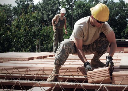 Spc. Robert Engeholm, a vertical engineer and team leader from Bloomington, Minnesota., works with a Croatian soldier to construct a ceiling with concrete blocks, June 15, 2015. Squads of Soldiers from the Little Falls, Minn.-based 851st Vertical Engineer Company have been rotating through Nasice, Croatia.