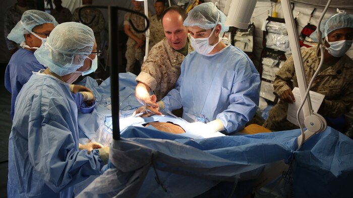 U.S. Navy Health Service Augmentation Program personnel and doctors with Naval Medical Center San Diego perform surgery on a mock casualty wearing a bleed suit during a field casualty training exercise at the Balboa Symposium, Naval Medical Center San Diego, June 18, 2015. The hospital corpsmen and field medical service technicians worked together to operate a field shock trauma and forward resuscitative surgical suite.