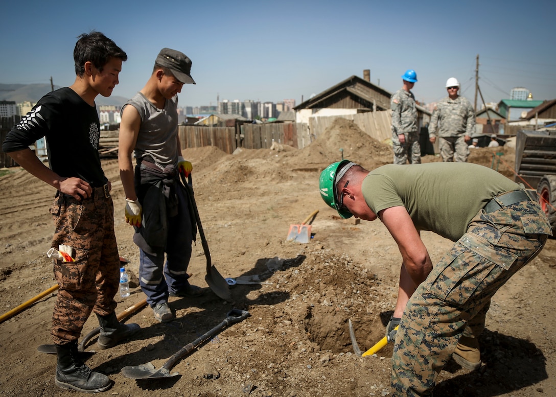 U.S. Marine Corps Lance Cpl. Cole Street, right, with 9th Engineer Support Battalion, 3rd Marine Logistics Group, assists Mongolian Armed Forces Junior Sgt. Ganaa Gankhurel, left, and Junior Sgt. Sube Batsumberel, middle, in digging holes for the base of fence posts surrounding the basketball court for the 55th Special Needs School during Khaan Quest 2015, in Ulaanbaatar, Mongolia, June 17, 2015. Khaan Quest is a regularly scheduled, multinational exercise hosted annually by Mongolian Armed Forces and co-sponsored by U.S. Army, Pacific, and U.S. Marine Corps Forces, Pacific. KQ15 is the latest in a continuing series of exercises designed to promote regional peace and security. This year marks the 13th iteration of this training event. 