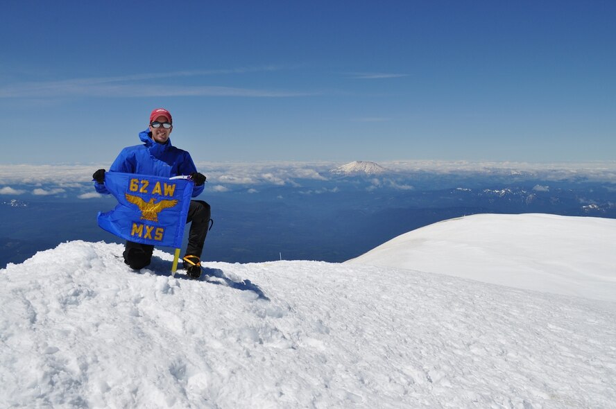 Maj. Clinton Varty, 62nd Maintenance Squadron commander, displays his squadron flag, June 14, 2015, on the summit of Mount Adams, Wash. The summit elevation for Mount Adams is 12,281 feet and this was the third of three mountains he climbed during his command of the 62nd MXS. (Courtesy photo)