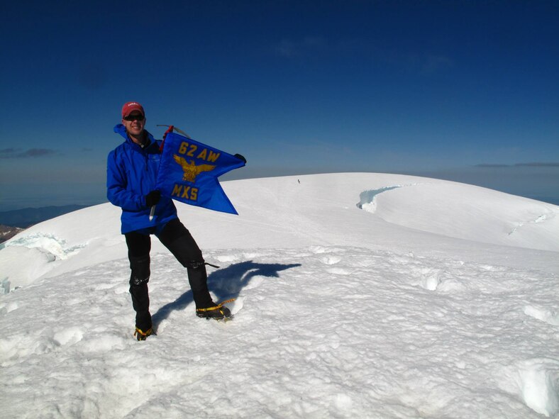 Maj. Clinton Varty, 62nd Maintenance Squadron commander, displays his squadron flag, June 9, 2014, on the summit of Mount Baker, Wash. The summit elevation for Mount Baker is 10,781 feet and this was the second of three mountains he climbed during his command of the 62nd MXS. (Courtesy photo)
