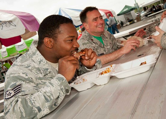 Staff Sgt. Jermain Smith, 5th Bomb Wing chaplain’s assistant, and Maj. Lance Giannone, 5th BW wing chaplain, eat ribs during the Magic City Ribfest in Minot, N.D., June 19, 2015. Ribfest hosted a military appreciation day allowing members of the base to try award winning ribs from across the United States. (U.S. Air Force photo/Airman 1st Class Sahara L. Fales)