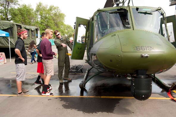 A member of the 54th Helicopter Squadron shows a UH-N1 Helicopter to community members during a military appreciation day at the Magic City Ribfest in Minot, N.D., June 19, 2015. Airmen representing different squadrons from Minot Air Force Base brought vehicles, gear and static displays to showcase our missions to members of the community. (U.S. Air Force photo/Airman 1st Class Sahara L. Fales)