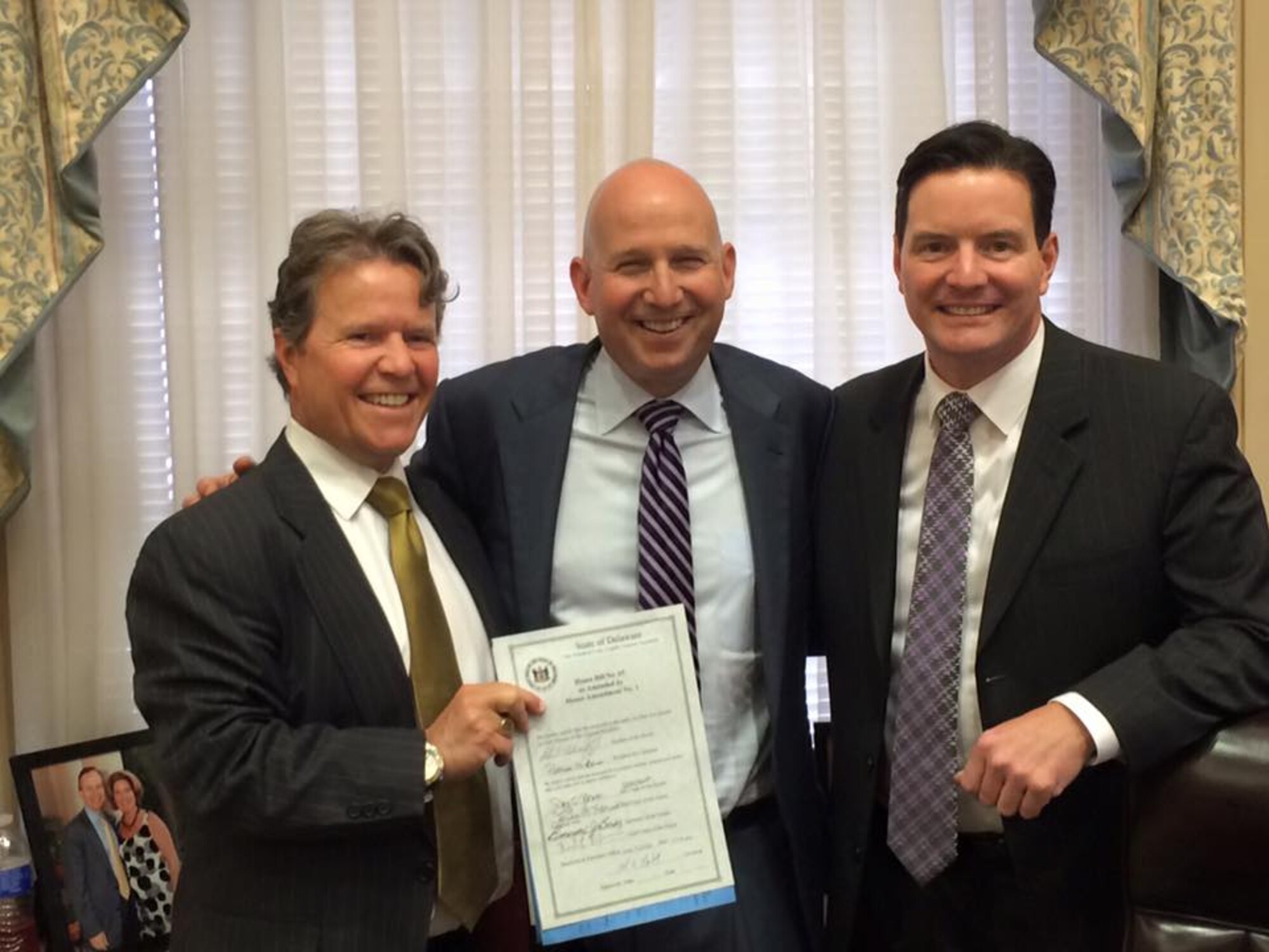 John Paradee (left), 512th Airlift Wing honorary commander, stands with his brother Delaware State Representative Trey Paradee (right) along side Delaware Governor Jack Markell in Dover, Del., June 10, 2015. Rep. Paradee is one of the sponsors of the state's Able Act, which the governor signed into law this day. (Courtesy photo)