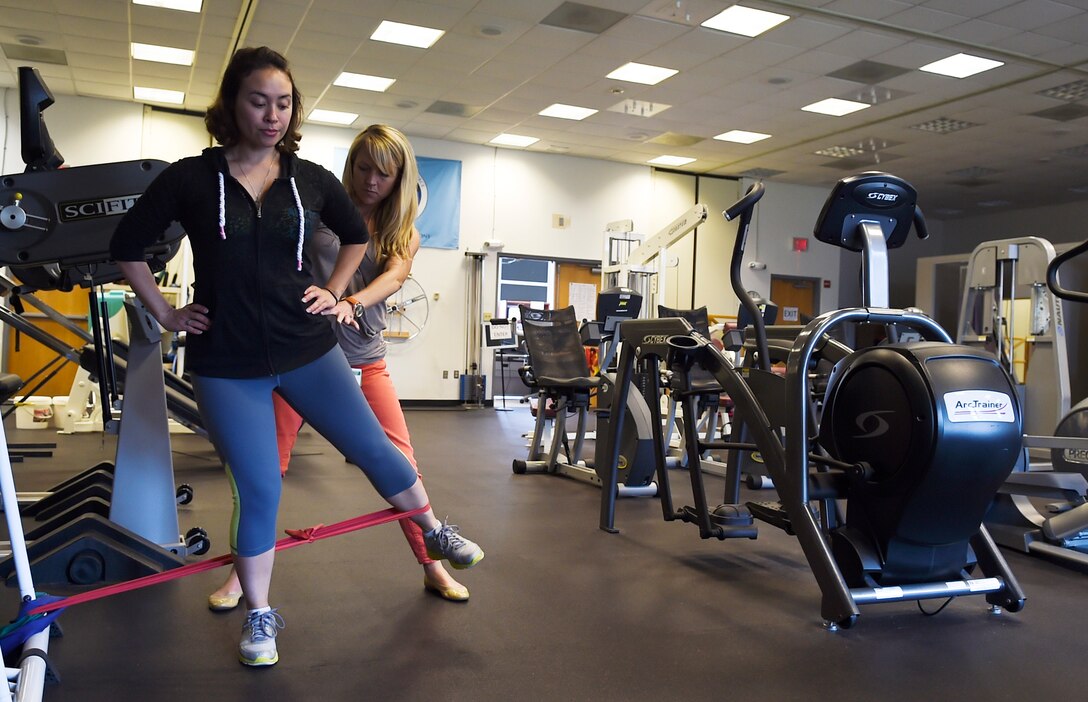 Tech. Sgt. Crystal Lee, Defense Information Systems Agency systems control watch officer, goes through an exercise with Dr. Katherine Rainey, 79th Medical Wing physical therapist, on Joint Base Andrews, Md., June 11, 2015. Lee progressed through her therapy and remains close with the staff that helped her along the way. (U.S. Air Force photo/ Senior Airman Mariah Haddenham/Released)