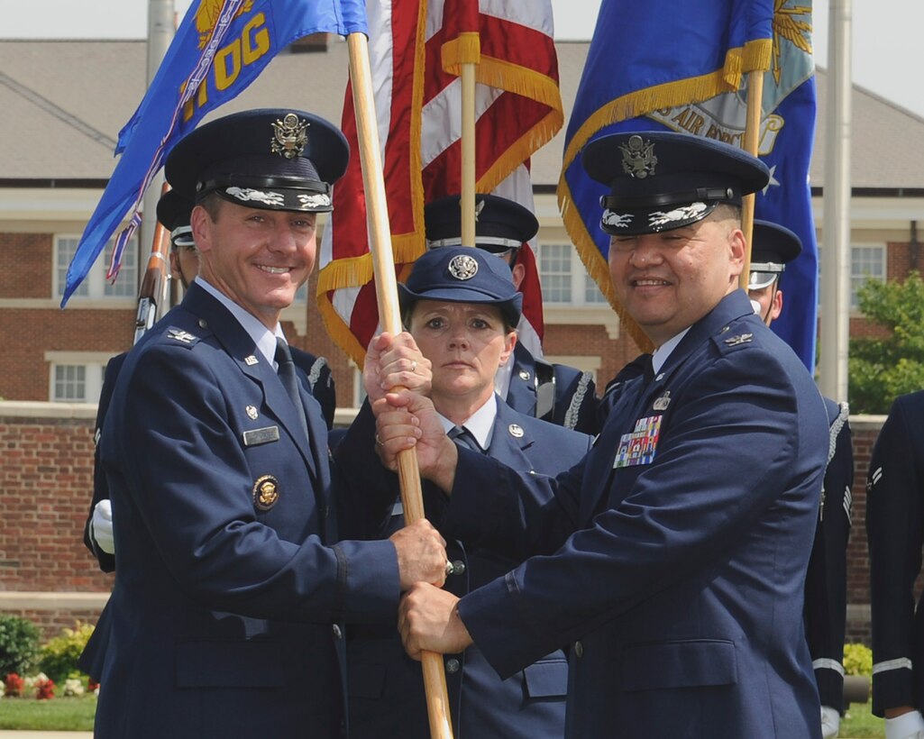 Col. Richard Lindlan, right, outgoing 11th Operations Group commander, relinquishes the 11 OG guidon to Col. Bradley Hoagland, 11th Wing/Joint Base Andrews commander, during the 11 OG change of command ceremony June 23, 2015, at Joint Base Anacostia-Bolling, District of Columbia. During his tenure, Lindlan commanded more than 460 chaplains, musicians, ceremonial guardsmen and staff in performing approximately 2,500 missions each year. (U.S. Air Force photo by Senior Airman Preston Webb/RELEASED)