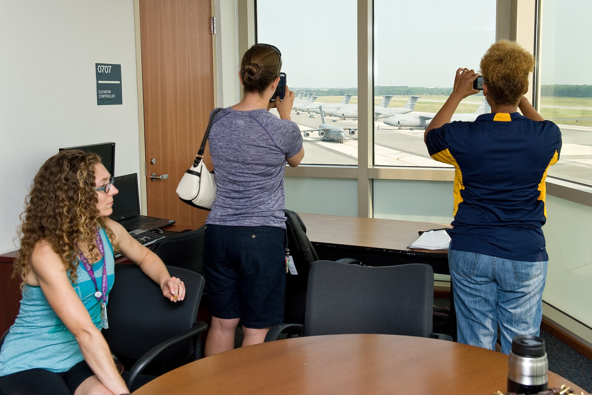 Cherylyn Minto, George S. Welch Elementary School art teacher, left, looks at the view of the airfield from the control tower breakroom June 12, 2015, on Dover Air Force Base, Del. Fellow school teachers shot pictures of a C-17 Globemaster III taxiing down the flight line as it makes it way to the runway preparing for departure. (U.S. Air Force photo/Roland Balik)