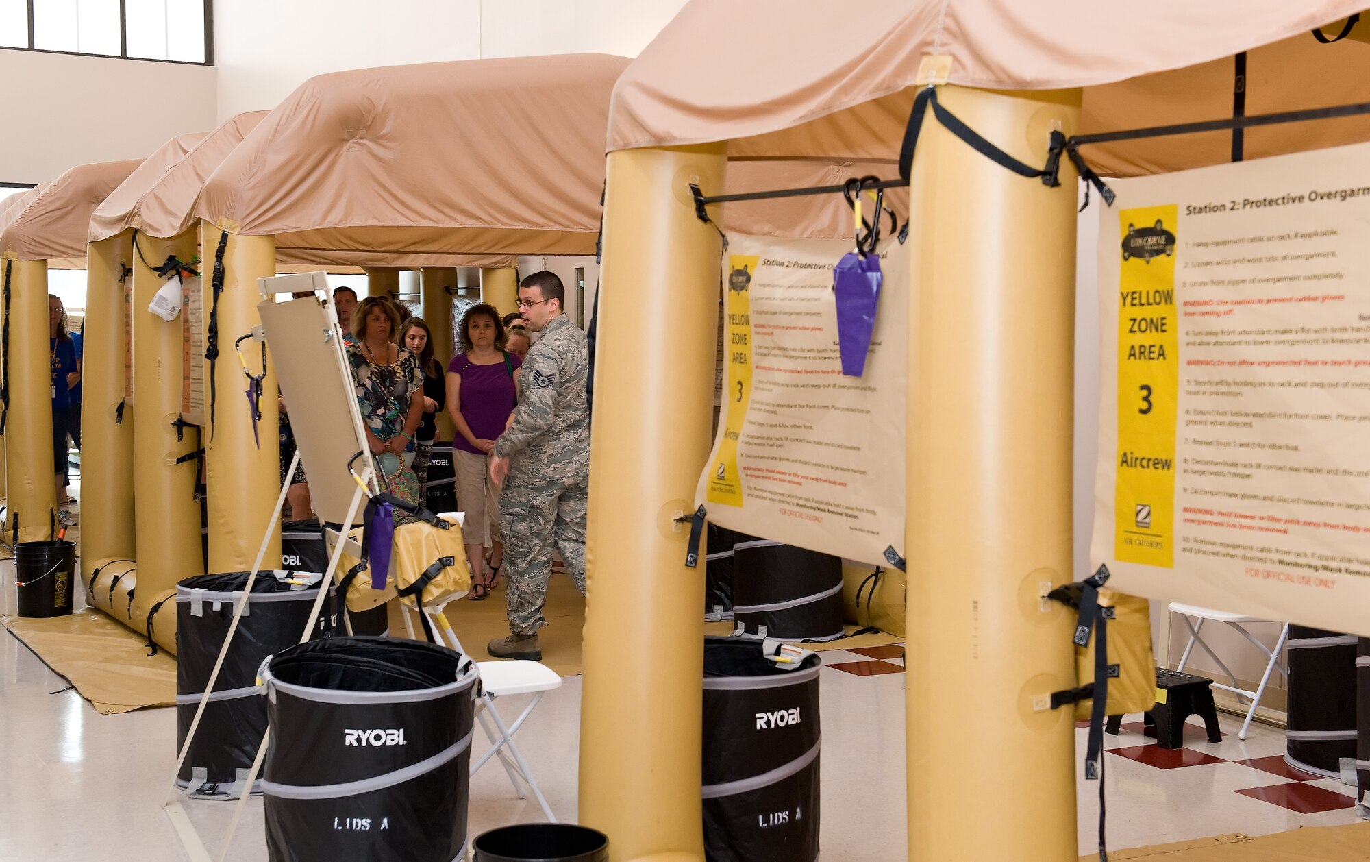 Staff Sgt. Jacob Johnson, 436th Operations Support Squadron aircrew flight equipment training instructor, center, walks local area school teachers through a mock aircrew decontamination line June 12, 2015, on Dover Air Force Base, Del. Johnson explained to the teachers decontamination procedures and the purpose of each of the four zones within the decontamination line. (U.S. Air Force photo/Roland Balik)