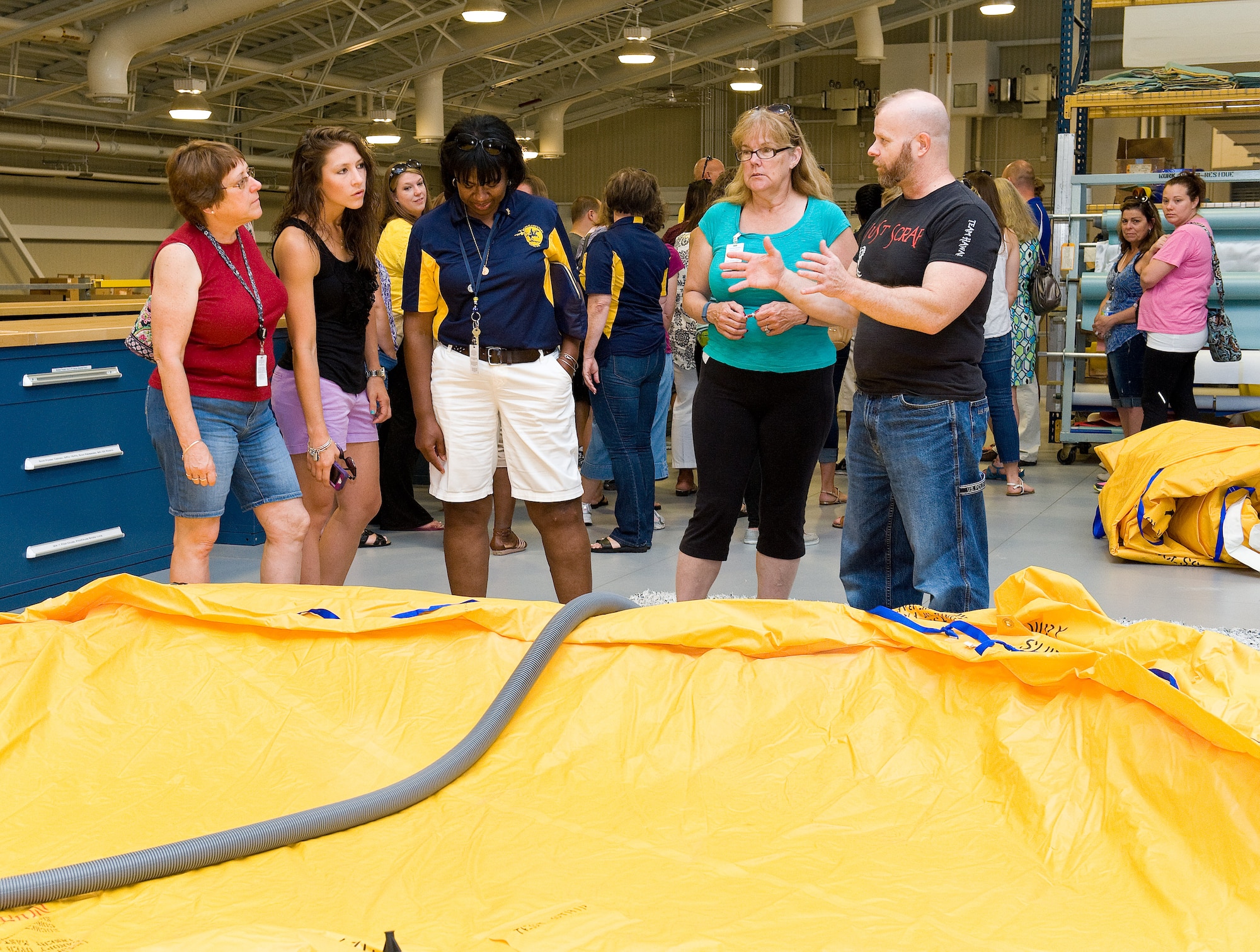 Dave Compton, 436th Operations Support Squadron aircrew flight equipment technician, right, describes the inspection process of a C-17 Globemaster III 46-man life raft to teachers from George S. Welch Elementary and Dover Air Force Base Middle schools June 12, 2015, on Dover Air Force Base, Del. The teachers received briefings on the duties of personnel and equipment located within the aircrew flight equipment section. (U.S. Air Force photo/Roland Balik)