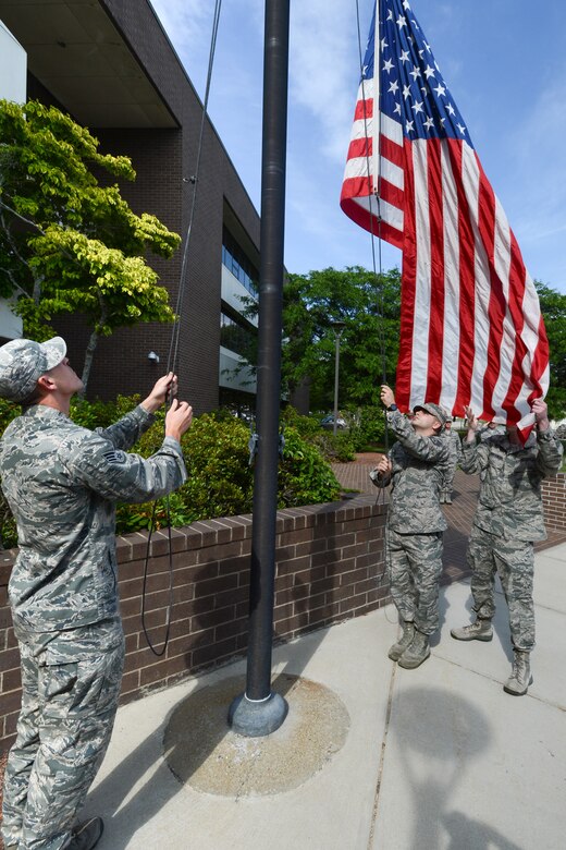 Senior Airman Gary Dennis (left), Staff Sgt. Michael Trala (center) and Airman 1st Class Aaron Wroblewski, all assigned to the 66th Medical Squadron, retrieve the flag during a formal retreat ceremony outside Building 1305, June 18. Members of 66 MDS participated in the retreat ceremony by retrieving the flag and providing a flight of clinic personnel. (U.S. Air Force photo by Jerry Saslav)